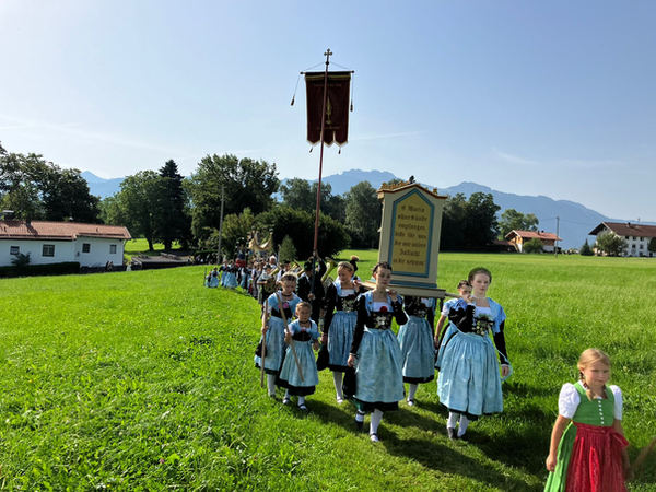 Kinderprozession mit Fahne über die Wiese